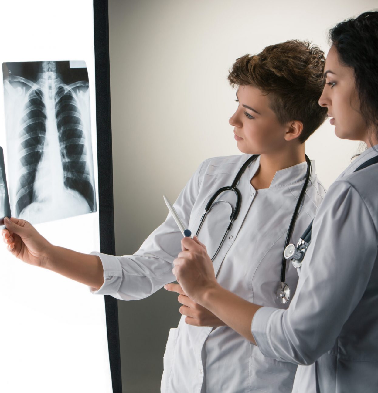 Two  attractive doctors looking at x-ray results on a gray background